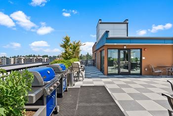 A modern building with a blue and orange exterior is surrounded by outdoor seating and a barbecue grill.