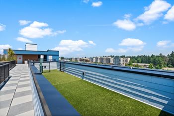 A modern building with a blue and white exterior is surrounded by a grassy area and a clear blue sky.