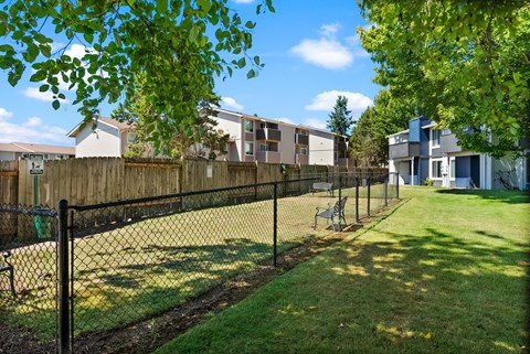 a fenced in yard with a bench in front of some apartments