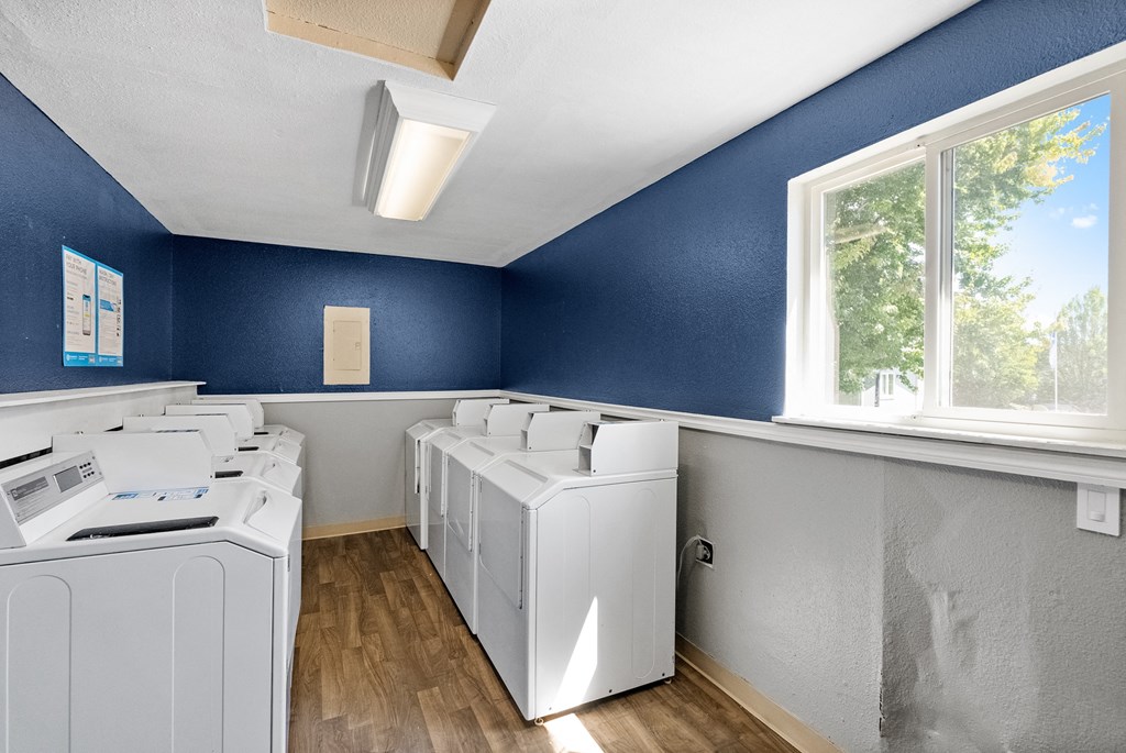an empty laundry room with washers and dryers and windows