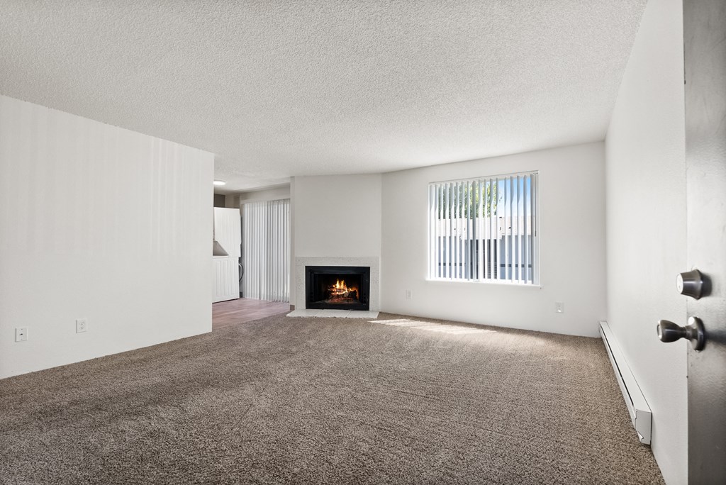 an empty living room with a fireplace and a window