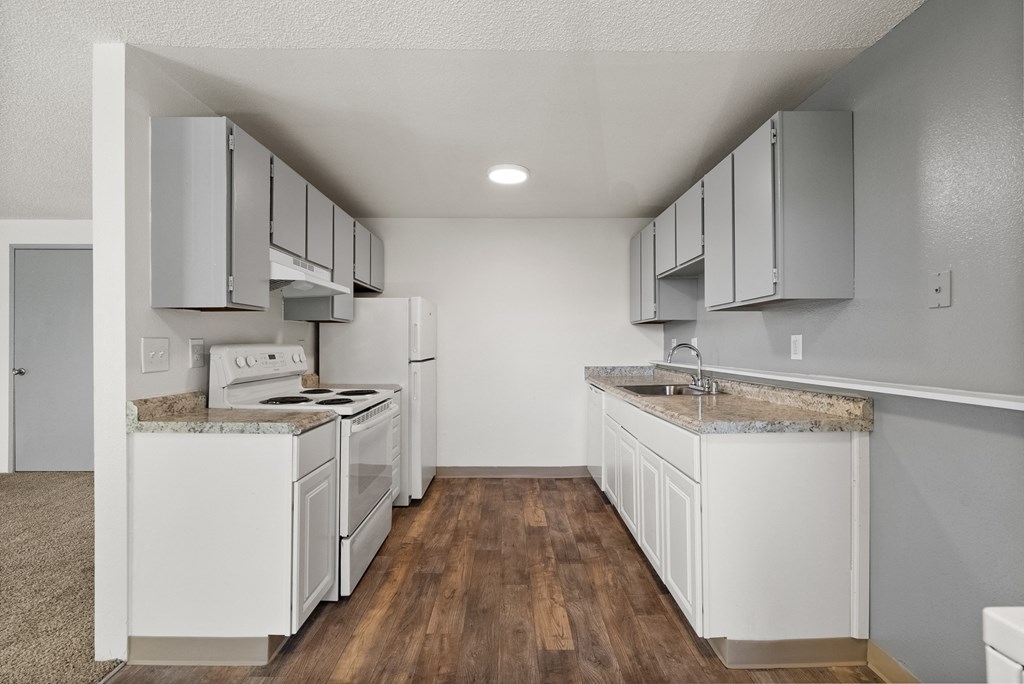 an empty kitchen with white appliances and white cabinets