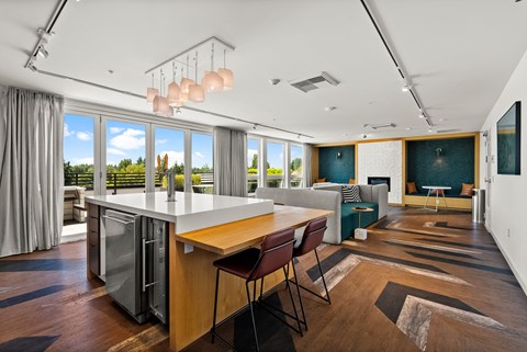A modern kitchen with a large island and a view of the trees outside.
