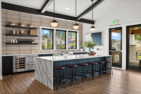 A kitchen with a marble counter top and bar stools.