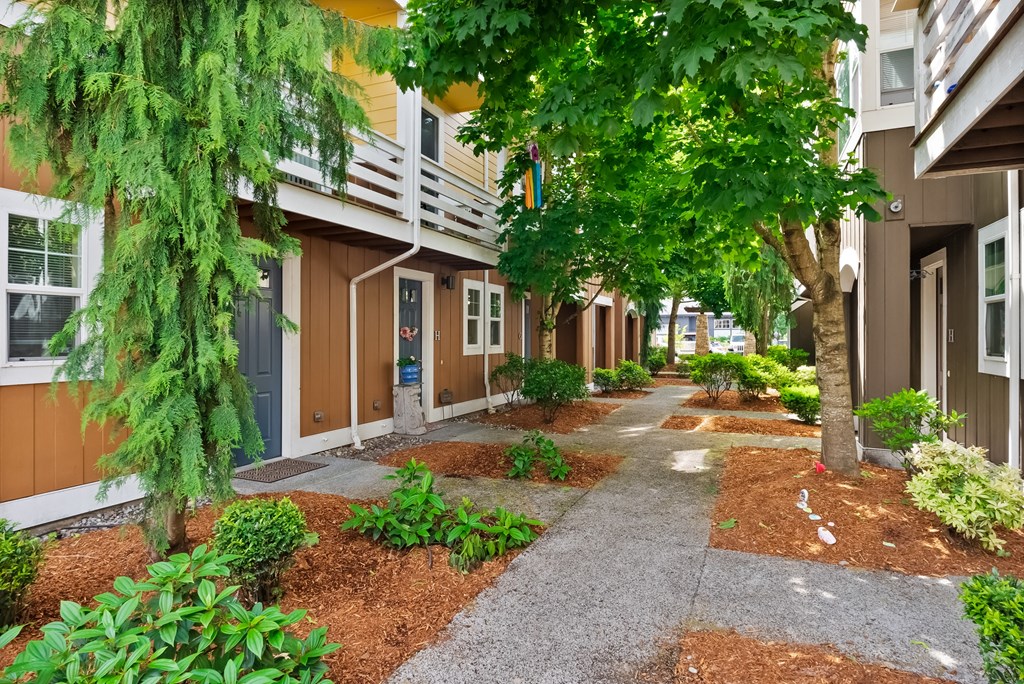 a walkway between two apartment buildings with trees and plants
