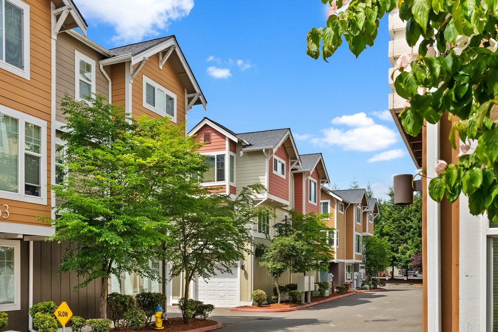 a row of townhouses with trees in front of a street