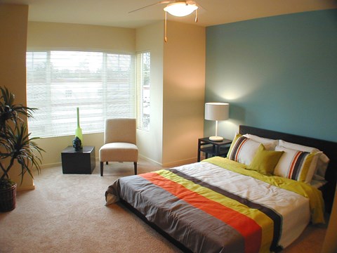 a bedroom with a bed and a chair and a window