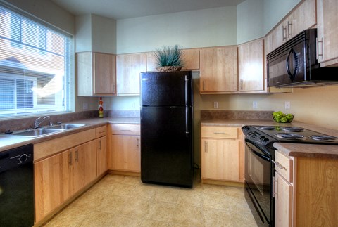 a kitchen with wooden cabinets and a black refrigerator