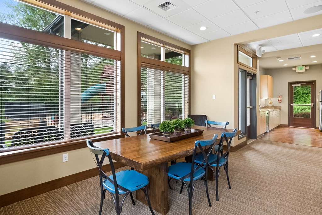a dining room with large windows and a wooden table with blue chairs