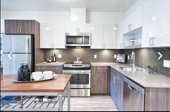 A modern kitchen with a wooden table, backsplashes, and stainless steel appliances.