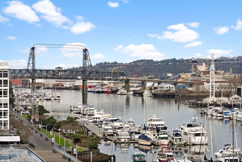 A marina with boats docked in the water and a bridge in the background.at The Henry, Tacoma, 98402