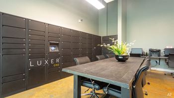 A room with a table, chairs and a wall with the word LUXER ONE on it.