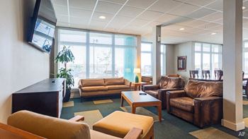 A living room with brown leather couches and a flat screen TV mounted on the wall.