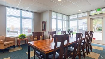A conference room with a long table and chairs, a couch, and a plant on a side table.