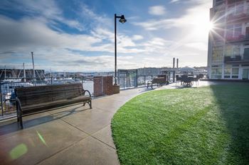 A bench is on a concrete walkway next to a grassy area.