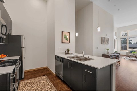 A modern kitchen with a black fridge and stove top oven.