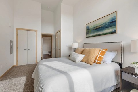 A bedroom with a large bed and a painting on the wall.