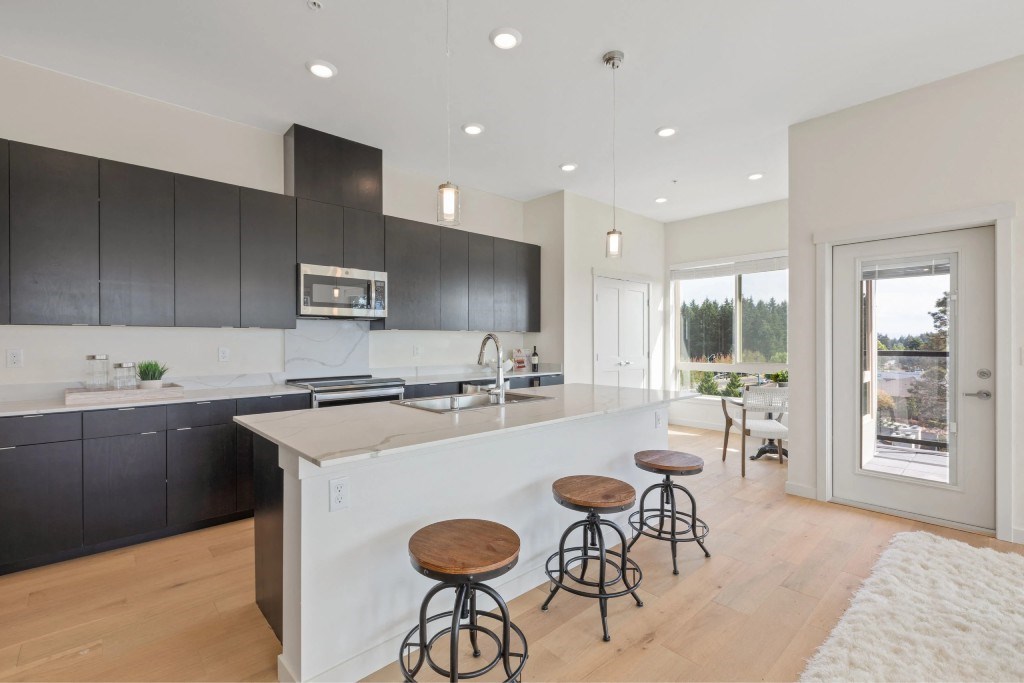 A kitchen with a white island and black cabinets.