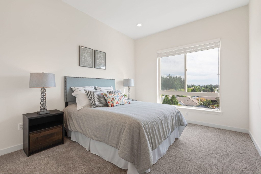 A bedroom with a bed, nightstand, and window.