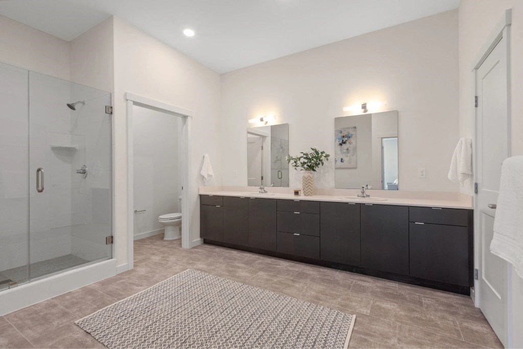 A bathroom with a walk-in shower, double sinks, and a large mirror.