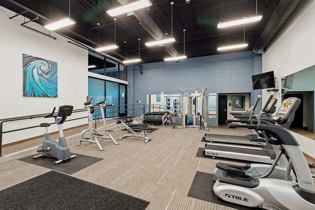 A gym with a variety of exercise equipment including treadmills, stationary bikes, and weight machines.