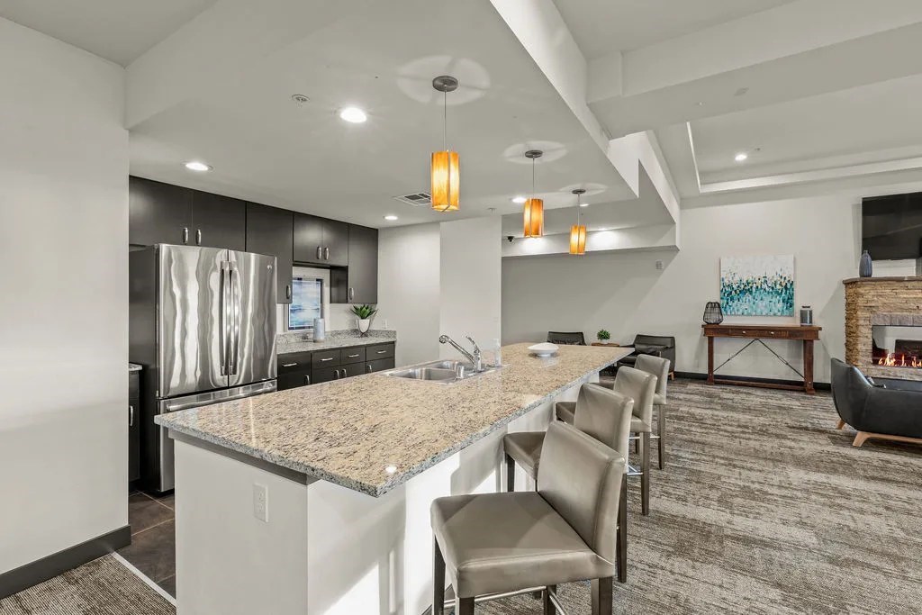 A kitchen with a granite countertop and a dining area with chairs.