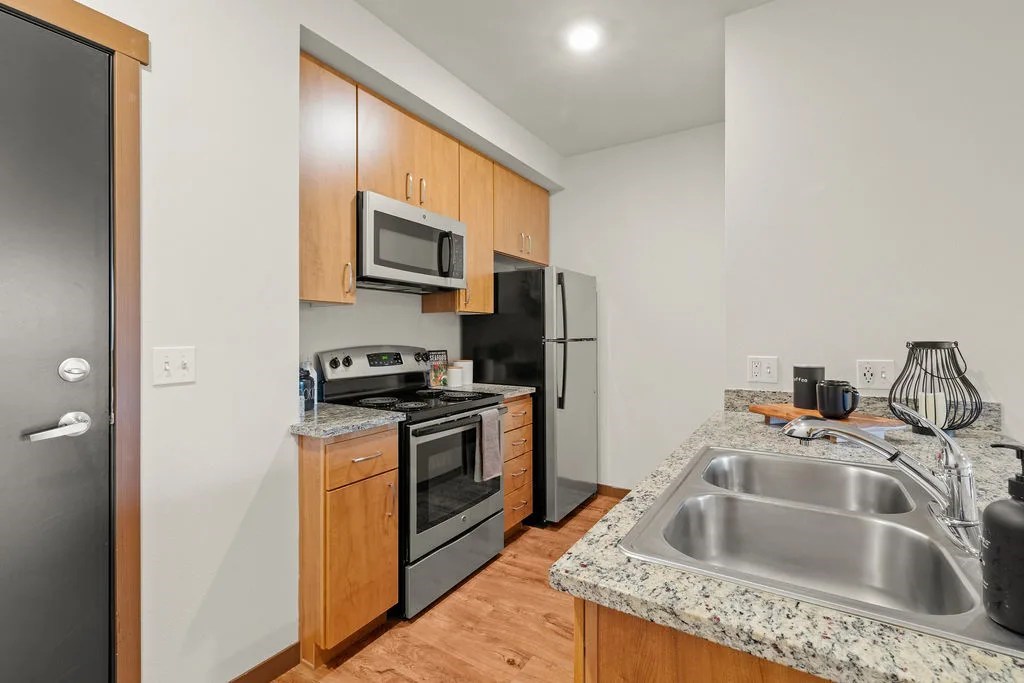 A kitchen with a sink, stove, and refrigerator.