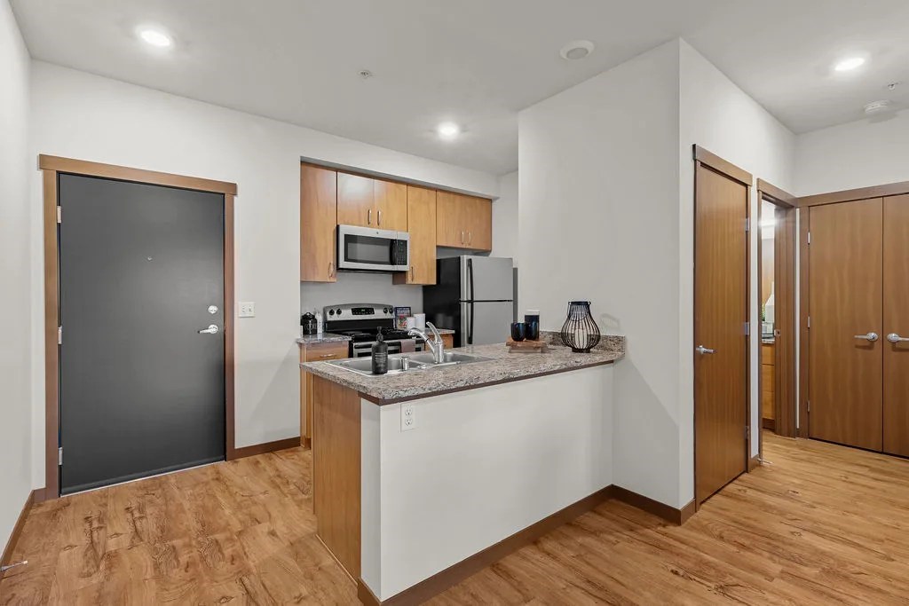 A kitchen with wooden cabinets and a black door.