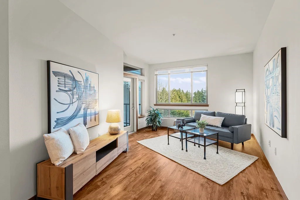 A modern living room with a large window and a view of trees outside.