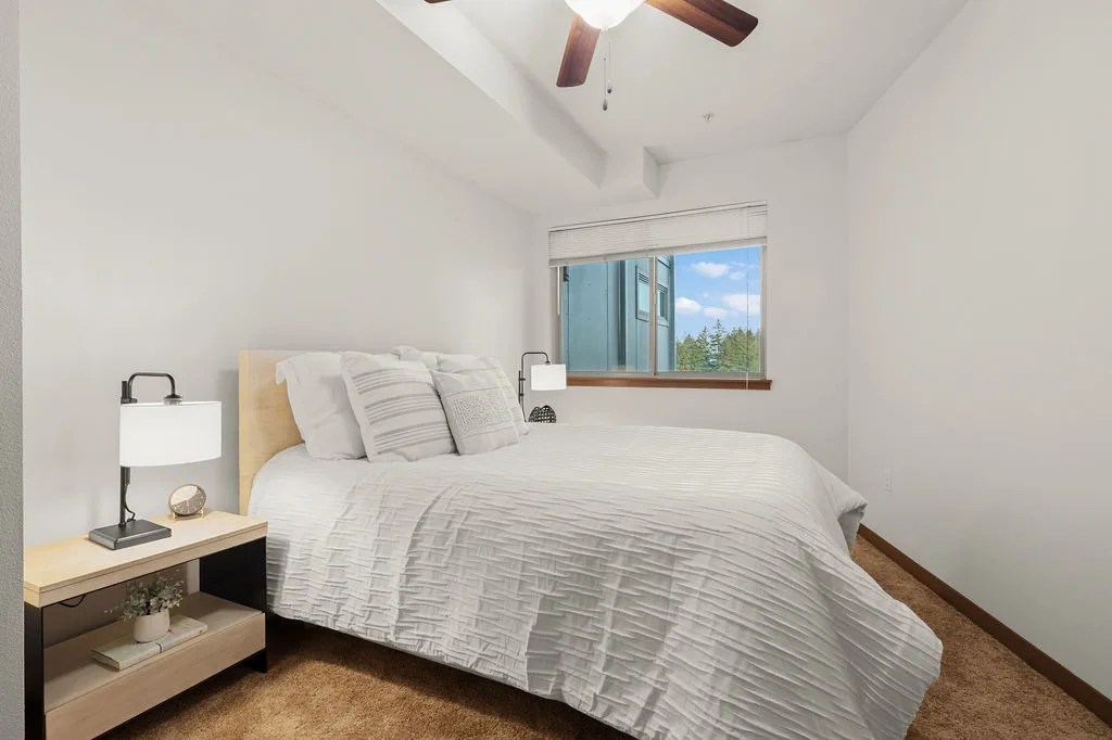 A bedroom with a bed, nightstand, and window.