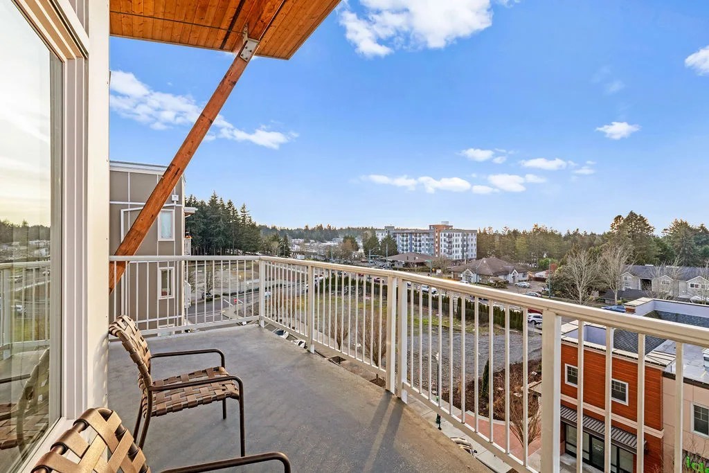 A balcony with a chair and a table overlooking a street.
