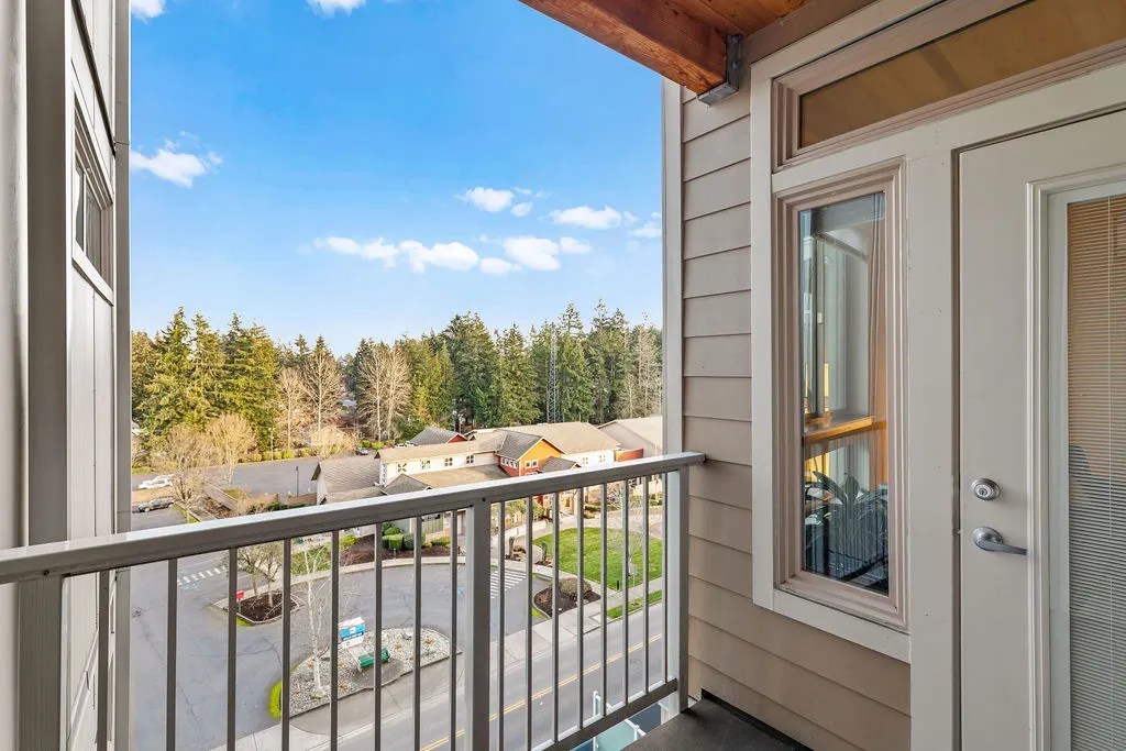 A balcony with a view of a parking lot and trees.