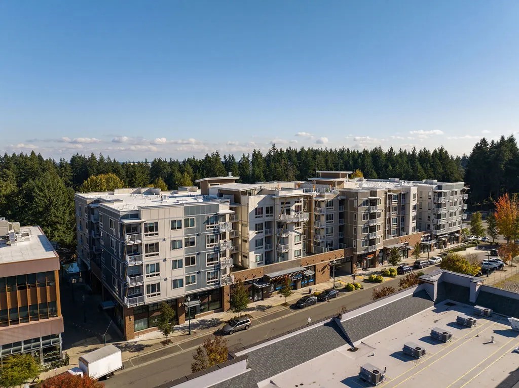 A large apartment complex is surrounded by trees and a parking lot.
