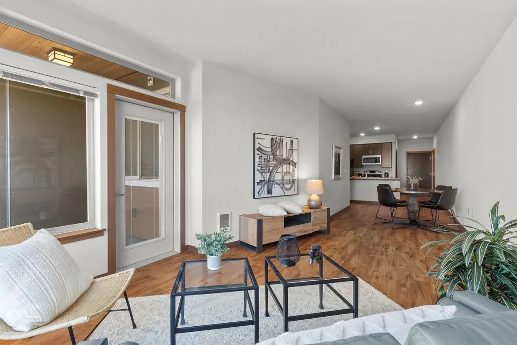 A living room with a glass door, a sofa, a chair, a coffee table, and a potted plant.