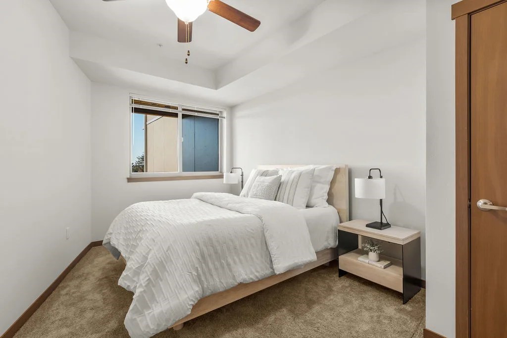 A bedroom with a bed, nightstand, and window.