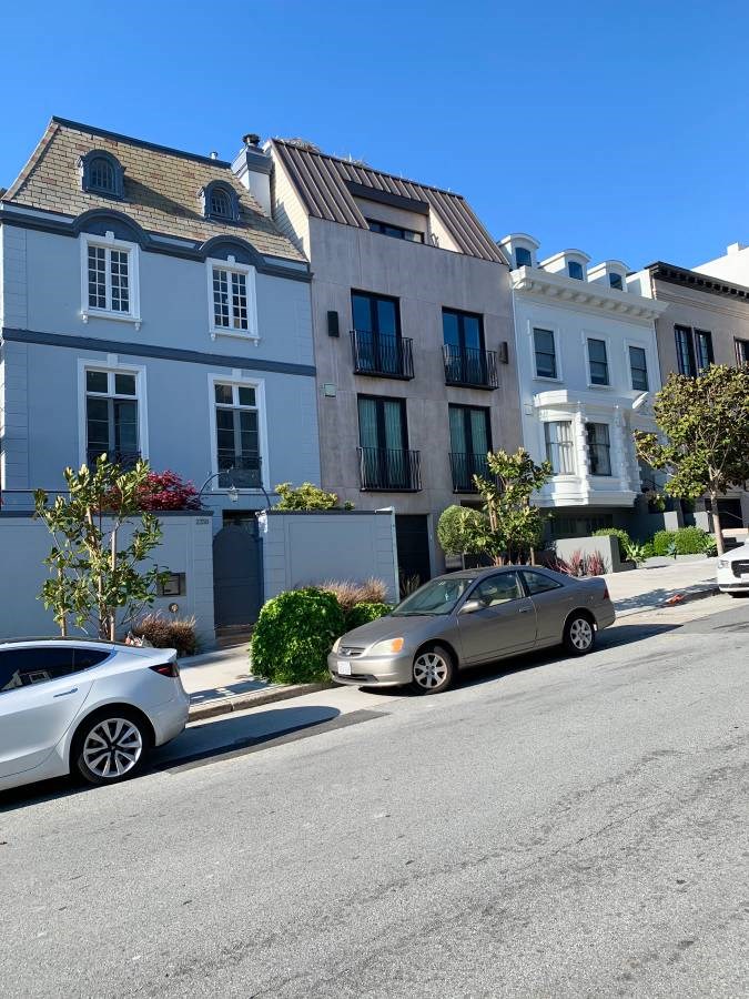 a row of houses on a street with cars parked in front