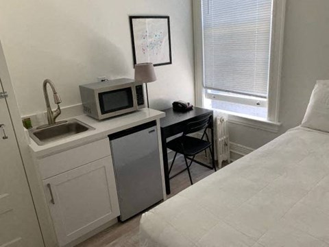 a small kitchen with a microwave and a sink in a bedroom