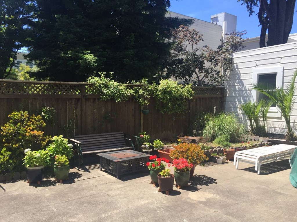 a patio with a bench and potted plants