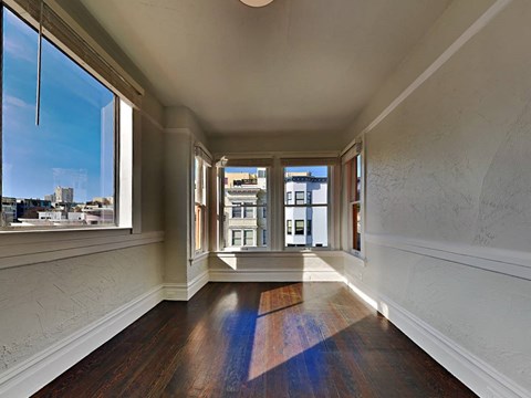 an empty living room with three windows and wood floors