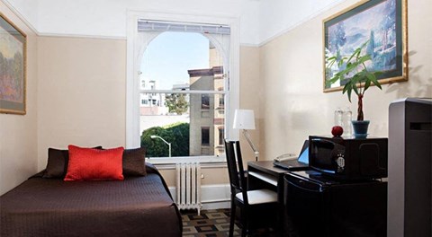 a bedroom with a bed and a desk and a window