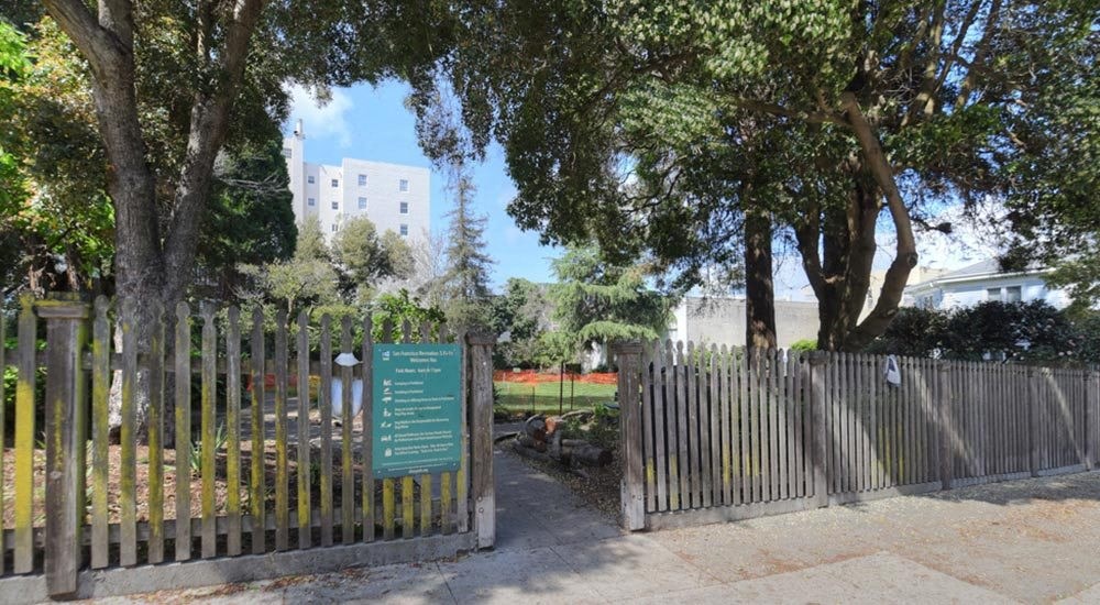 a park with a fence and trees and a sign
