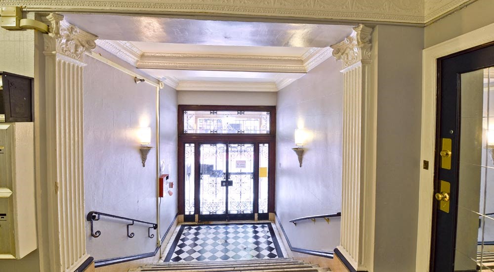 the lobby of a building with a door and a checkered floor