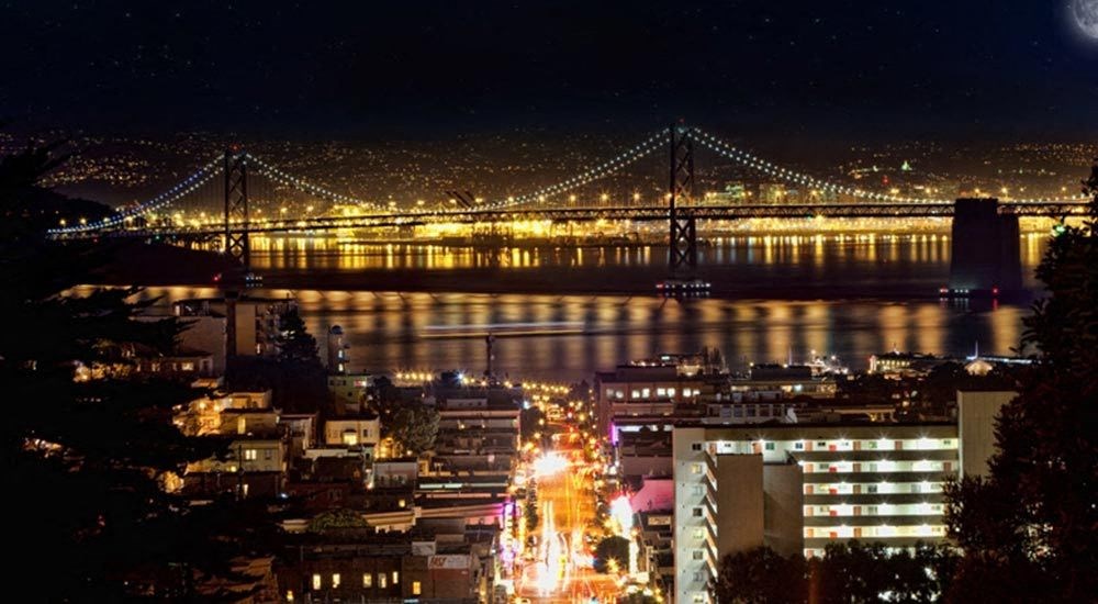 a city at night with a bridge and a river