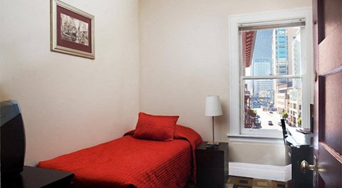 a small bedroom with a red bed and a window