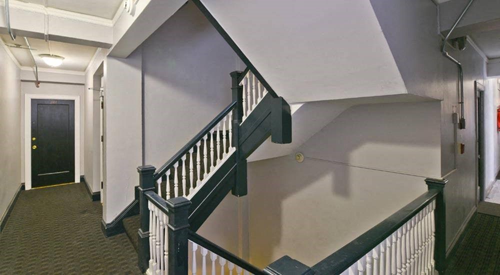 a stairway with a wooden railing and a black door