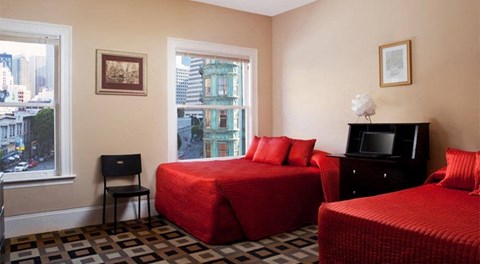 a bedroom with two red beds and a tv