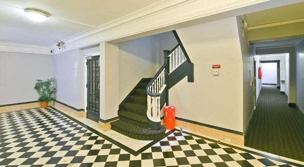 the lobby of a building with a staircase and a checkered floor