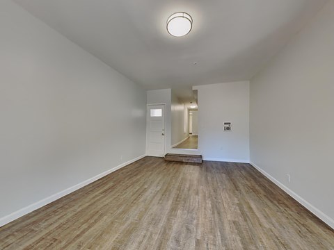 a spacious living room with white walls and wood floors