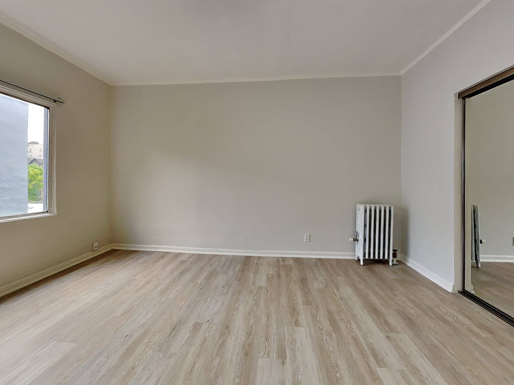 a room with wooden floors and a window and a radiator