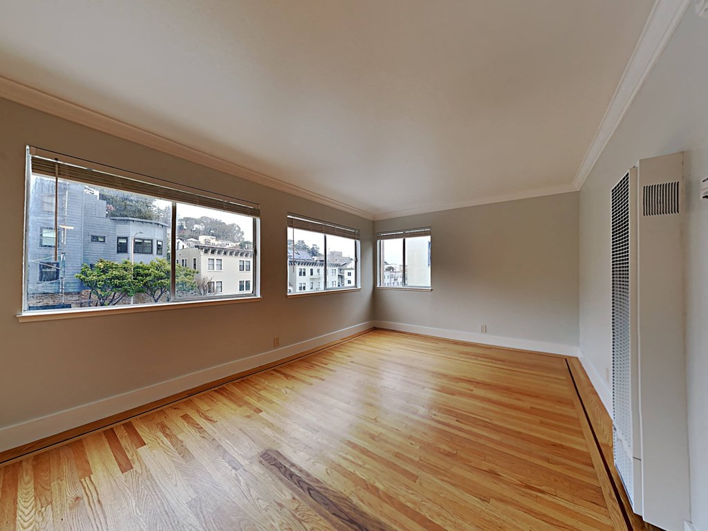 an empty living room with wood floors and large windows